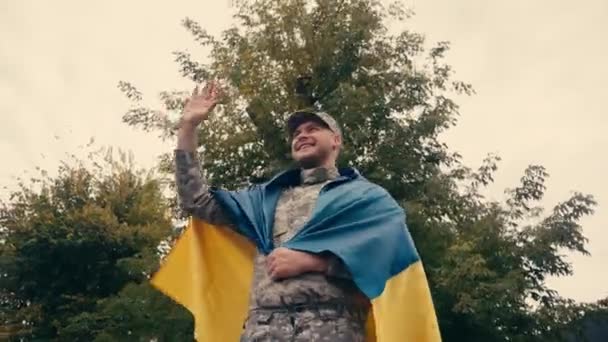 举着乌克兰国旗和户外散步时挥手微笑的士兵 — 图库视频影像