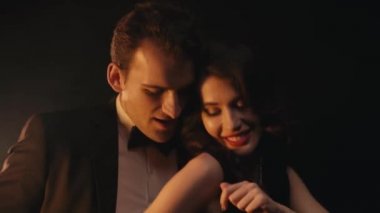 Siyah arka planda dans ederken gülen neşeli ve şık bir çift