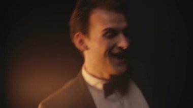 Siyah arka planda dans eden takım elbiseli neşeli genç adam.