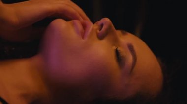 Dudaklara dokunan ve arka planda uzanan seksi bir kadın.