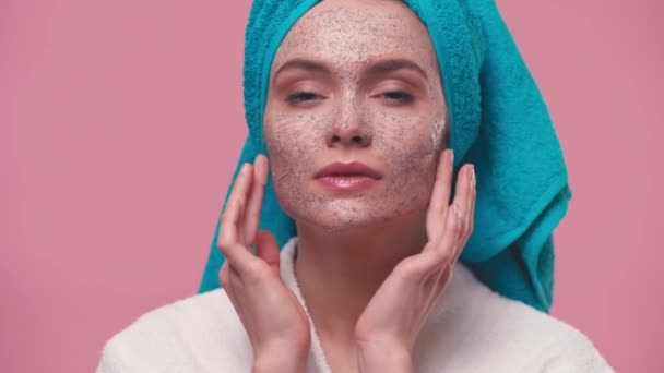 Mulher Com Toalha Cabeça Aplicando Esfoliação Facial Isolado Rosa — Vídeo de Stock