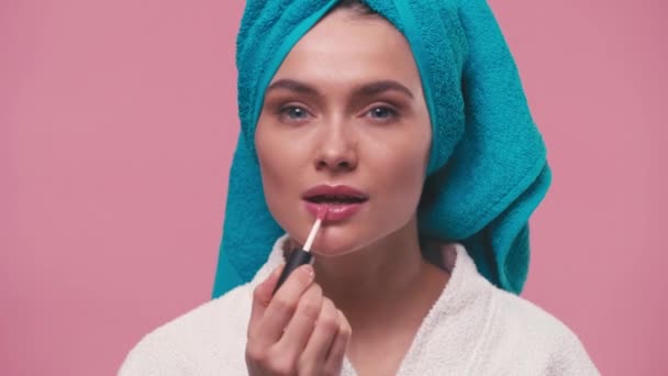 Νεαρή Γυναίκα Εφαρμογή Lip Gloss Και Χαμογελά Απομονωμένη Ροζ — Αρχείο Βίντεο