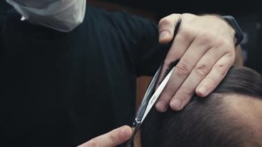 Tıbbi maskeli berber görüşü berber dükkanında müşteriyi kesiyor. 