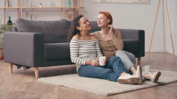 Redhead Woman Hugging Hispanic Girlfriend Cup Living Room — Stock Video