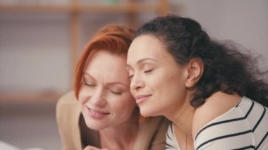 Evde gülümseyen gözleri kapalı mutlu ırklar arası kız arkadaşlar.