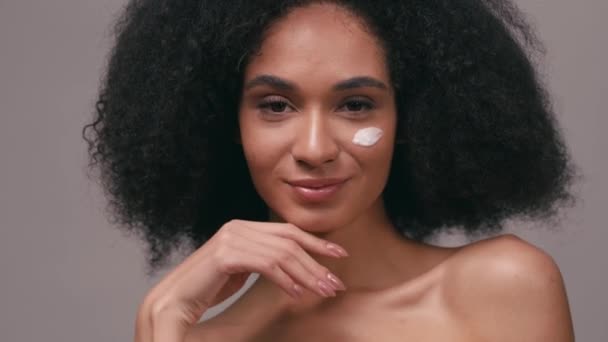 Uśmiechnięta Afroamerykanka Kremem Kosmetycznym Twarzy Wyizolowana Szaro — Wideo stockowe