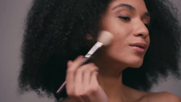 Mujer Afroamericana Aplicando Iluminador Con Cepillo Cosmético Aislado Gris — Vídeos de Stock