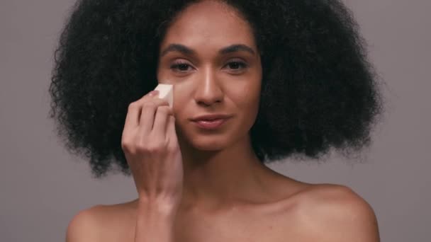 Mulher Afro Americana Aplicando Fundação Maquiagem Com Esponja Isolada Cinza — Vídeo de Stock