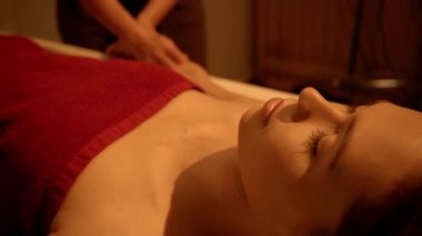 Kapalı gözlü genç kadın spa salonunda masaj yaptırıyor.