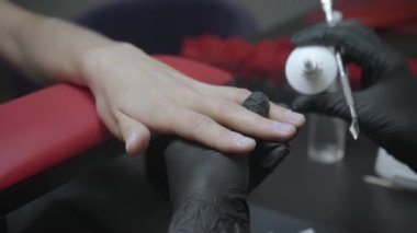 Manikürcünün manikürcü yağı döküp tırnak içi ilacı kullanmasının kısmi görüntüsü