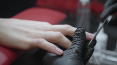 Müşterinin tırnaklarını törpüleyen manikürcünün kısmi görünümü 