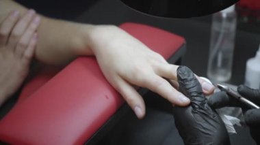 Manikürcüde profesyonel manikür yaptıran bir kadının kısmi görüntüsü 