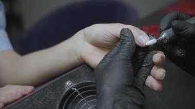Lastik eldivenli güzellik uzmanının müşterinin tırnaklarını cilalarkenki kısmi görüntüsü