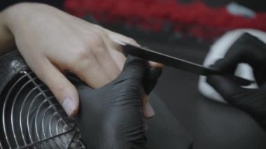 Lastik eldivenli güzellik uzmanının müşterinin tırnaklarını törpülediği kısmi manzara