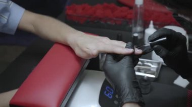 Tıbbi maskeli güzellik uzmanının parmağına oje sürerken kısmi görüntüsü