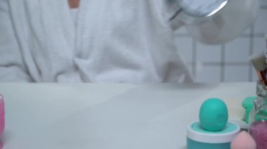 Bornozlu kadının masaya alarmlı saat koyuşunun kısmi görüntüsü