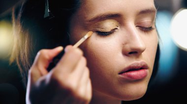 makeup artist applying concealer on eyelid of model clipart