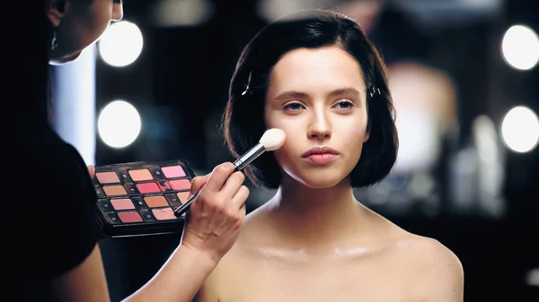 Maquillador Sosteniendo Paleta Aplicando Resaltador Cara Mujer — Foto de Stock