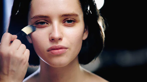 Makeup Artist Håller Kosmetisk Borste Samtidigt Som Makeup Foundation Ansiktet — Stockfoto