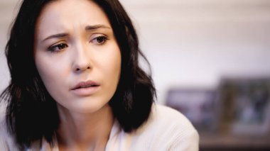 portrait of depressed brunette woman in beige sweater at home clipart