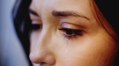 close up view of upset woman crying with tears on face on grey background clipart