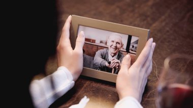 Evde yaşlı bir adamın fotoğrafının olduğu kadın eli çerçevesinin kısmi görüntüsü