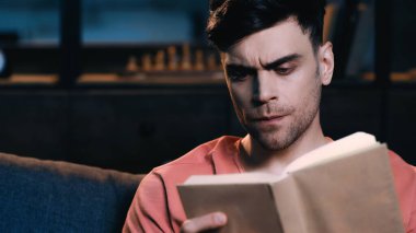 Evde kitap okumaya odaklanmış bir adam 