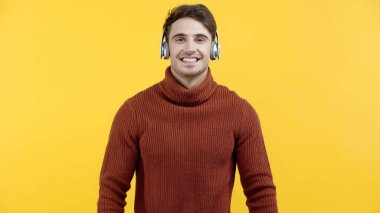 Sarıda izole edilmiş kameraya gülümseyen kulaklı yakışıklı bir adam. 