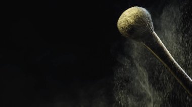 Siyah zemin üzerinde sarı holi tozu olan yumuşak kozmetik fırçası