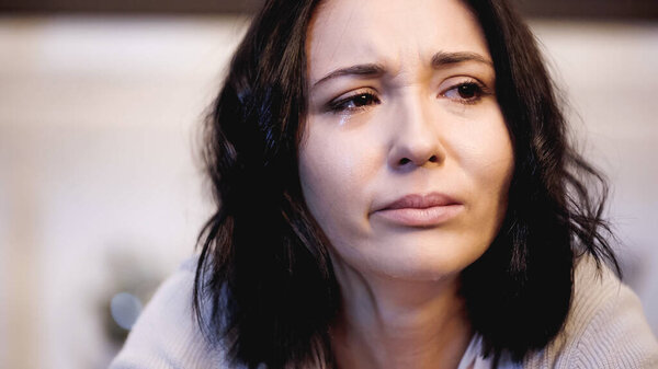 close up view of upset woman crying with tears on face at home