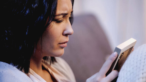 depressed woman sitting on sofa with photo frame at home