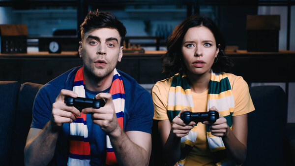 KYIV, UKRAINE - JUNE 09, 2021: couple in striped scarfs playing video game 