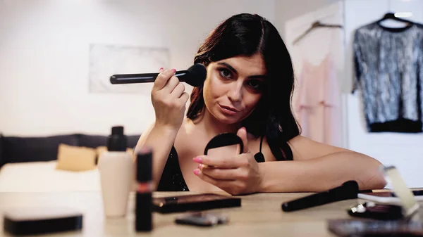 Brunett Ung Kvinna Tillämpa Ansiktspulver Nära Bordet Med Dekorativa Kosmetika — Stockfoto