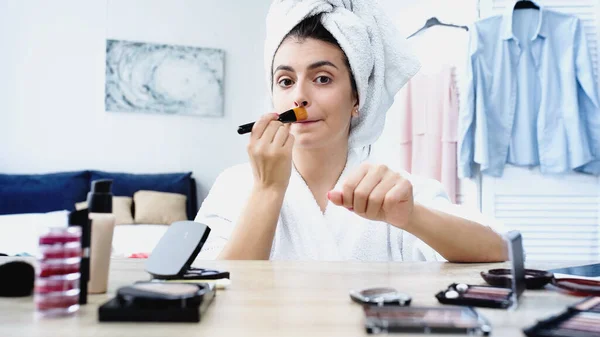 Young Woman Bathrobe Head Wrapped Towel Applying Face Foundation Table — Stock Photo, Image