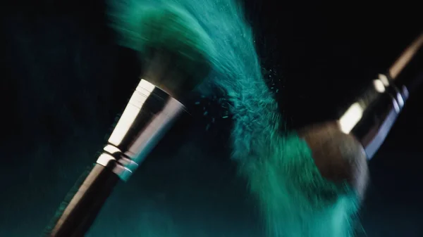Blurred Cosmetic Brushes Vibrant Turquoise Holi Paint Splashing Black Background — Stock Photo, Image