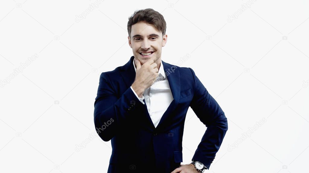 Cheerful businessman holding hand near chin isolated on white 