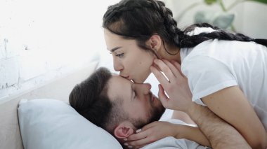 young brunette woman kissing nose of boyfriend  clipart