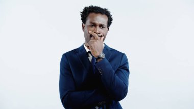 Resmi giysili dalgın Afro-Amerikan iş adamı mavi üzerine izole edilmiş olarak bakıyor ve düşünüyor.