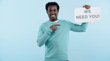 Memnun Afro-Amerikalı adam konuşma balonunu işaret ederek mavi üzerine izole harfler yazmanı istiyoruz.