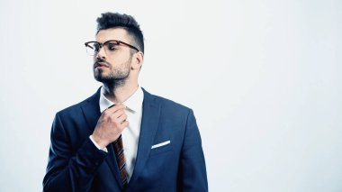 Gözlüklü kendine güvenen iş adamı kravatını düzeltiyor.