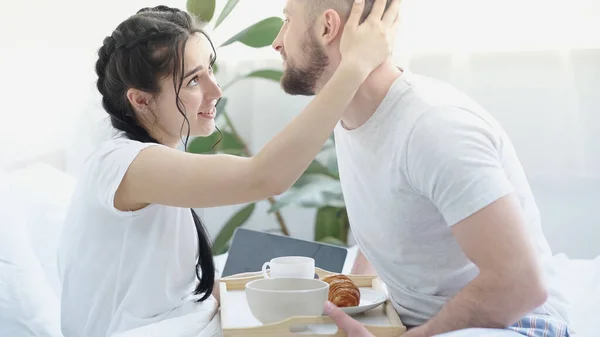 笑着的女朋友 辫子拥抱着快乐的男朋友 带着早餐盘在床上 — 图库照片