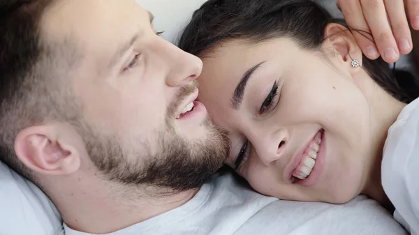快乐的黑发女人躺在床上靠在长胡子的男朋友上 — 图库照片