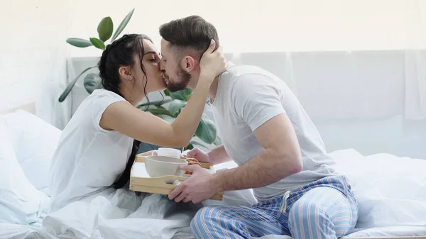 Bärtiger Mann Bringt Freundin Mit Zöpfen Frühstückstablett Beim Küssen Schlafzimmer — Stockfoto