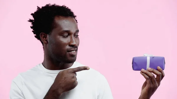 Счастливый Африканский Американец Белой Футболке Указывая Завернутый Подарок Изолирован Розовый — стоковое фото