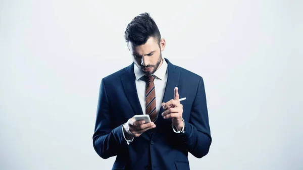 Przemyślany Biznesmen Pokazując Gest Uwagi Podczas Korzystania Telefonu Komórkowego Odizolowany — Zdjęcie stockowe