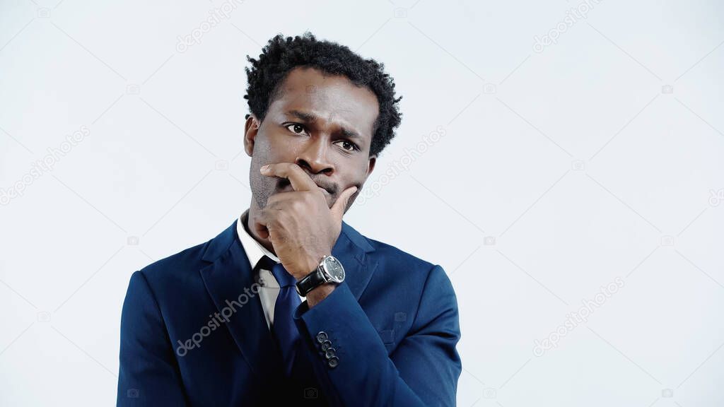 thoughtful african american businessman in suit looking away isolated on blue
