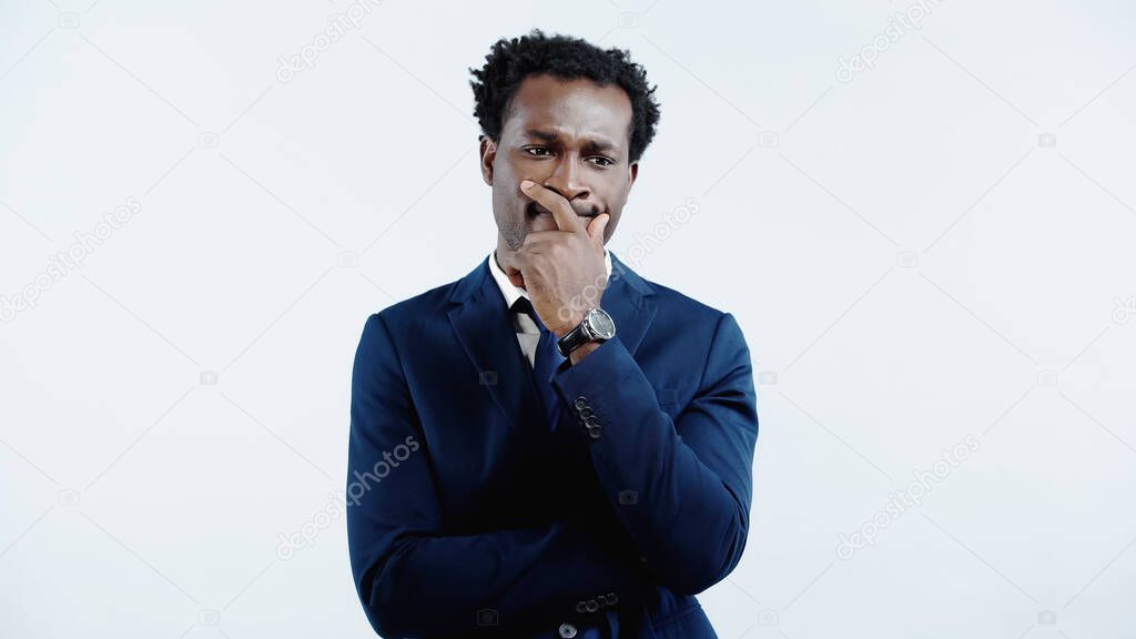 pensive african american businessman in formal wear looking away and thinking isolated on blue