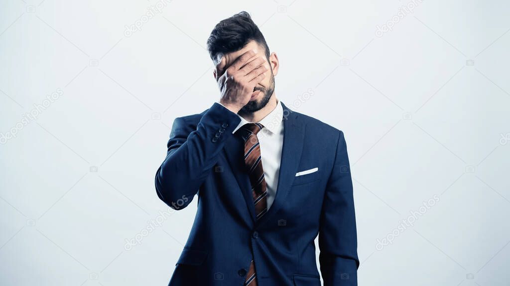 depressed businessman covering eyes with hand isolated on white