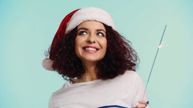 Mutlu kadın Noel Baba şapkalı, elinde maytap tutan mavi tenli.