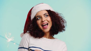 Noel Baba şapkalı, maytaplı, mavi tenli genç bir kadın. 